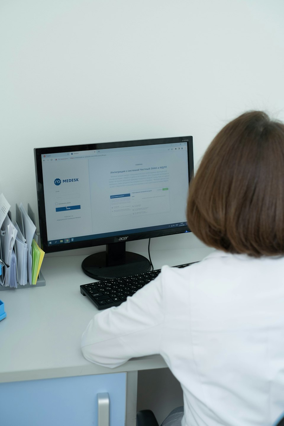 Medical professional using computer software at a clean desk.