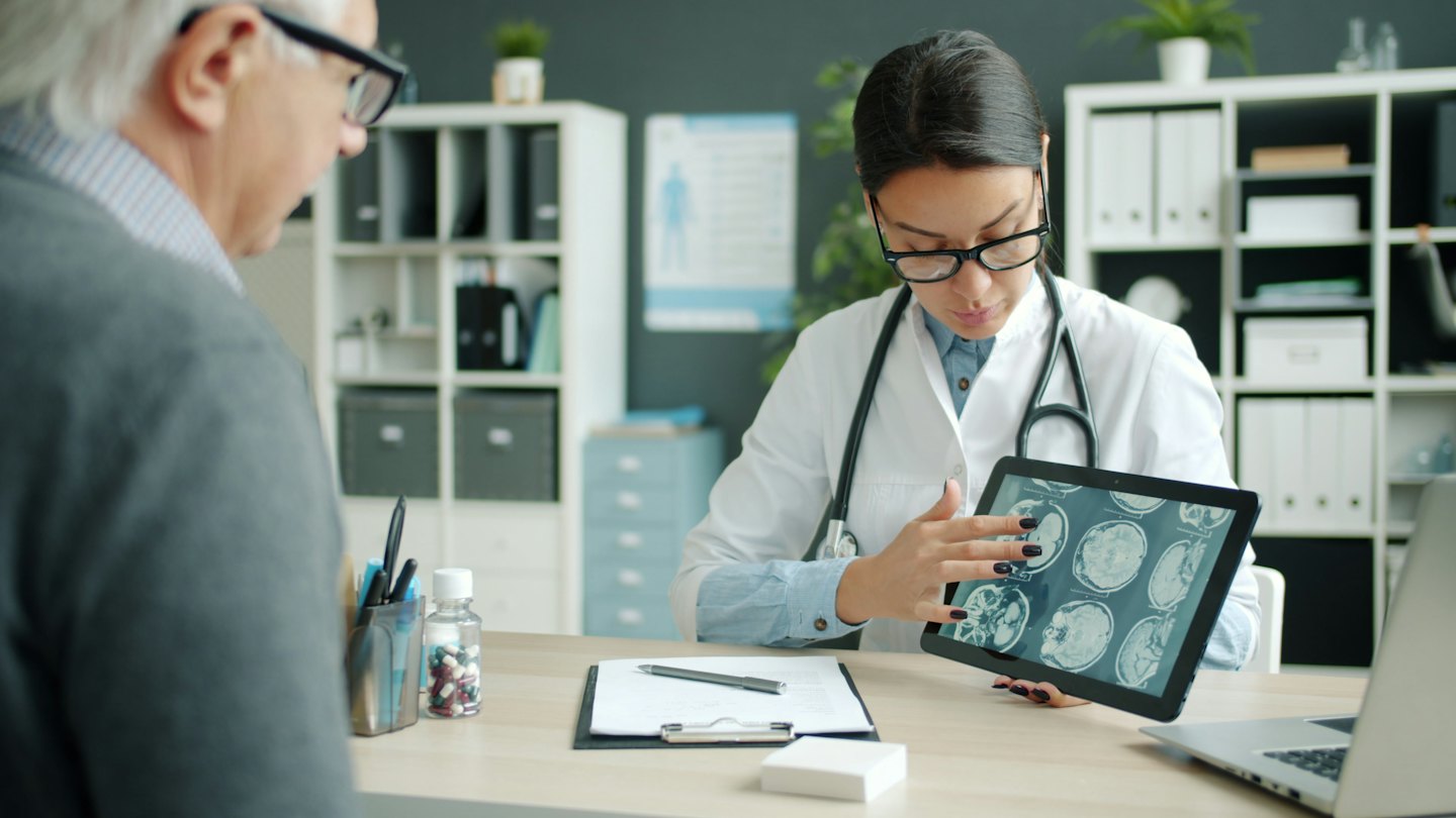Doctor explaining medical scans on a tablet to a patient.